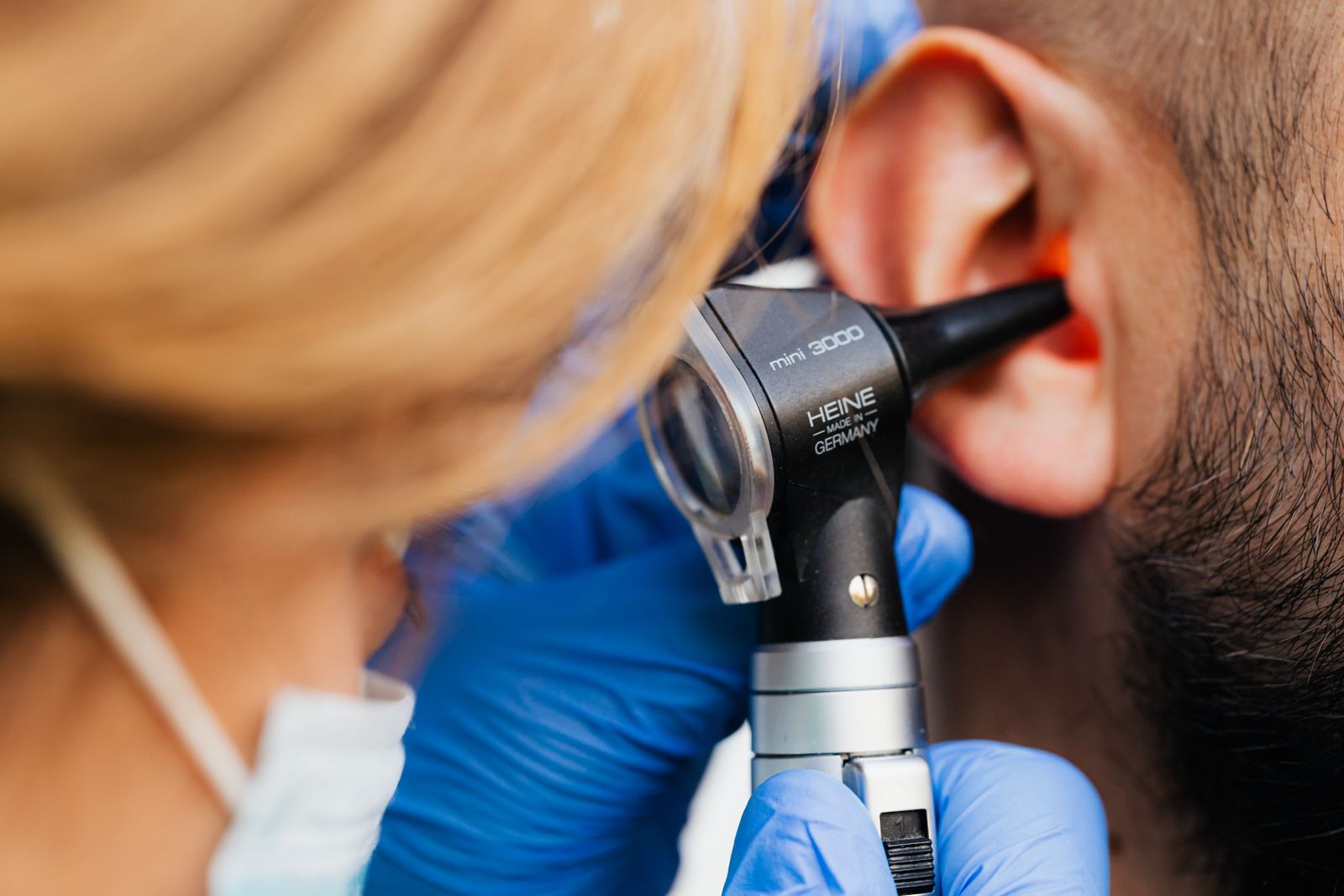 Audiologist examining a smiling patient's ear in a bright clinic